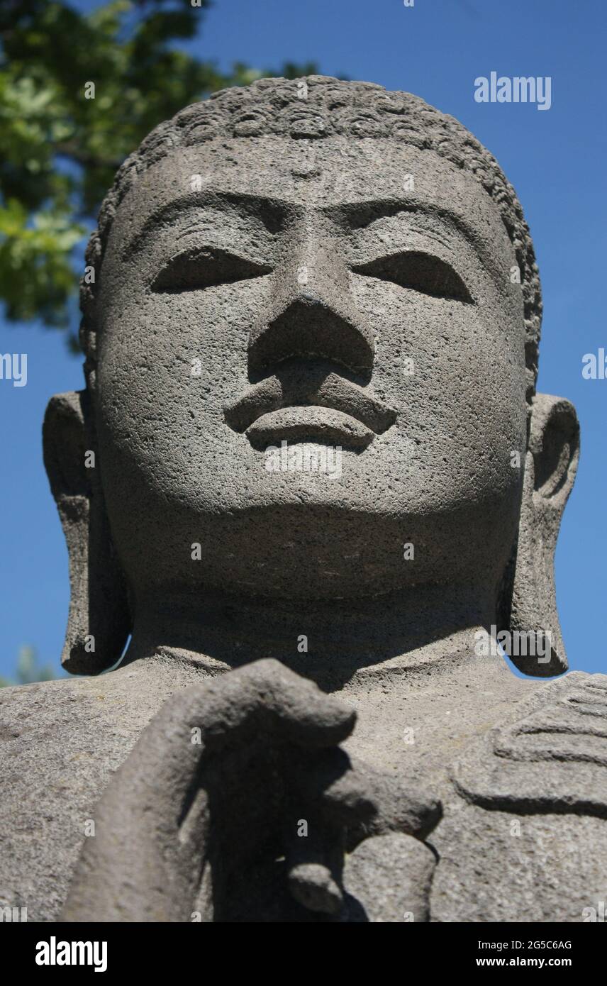 Testa di una statua di Buddha grigia in una giornata di sole Foto Stock