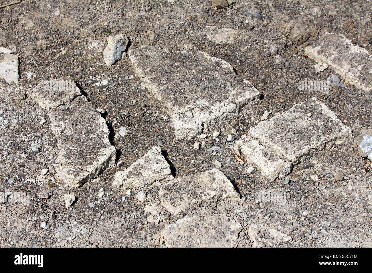 Parti rotte di cemento distrutto marciapiede pubblico mescolato con sabbia e ghiaia di fronte alla vecchia casa suburbana famiglia in caldo sole primavera giorno Foto Stock