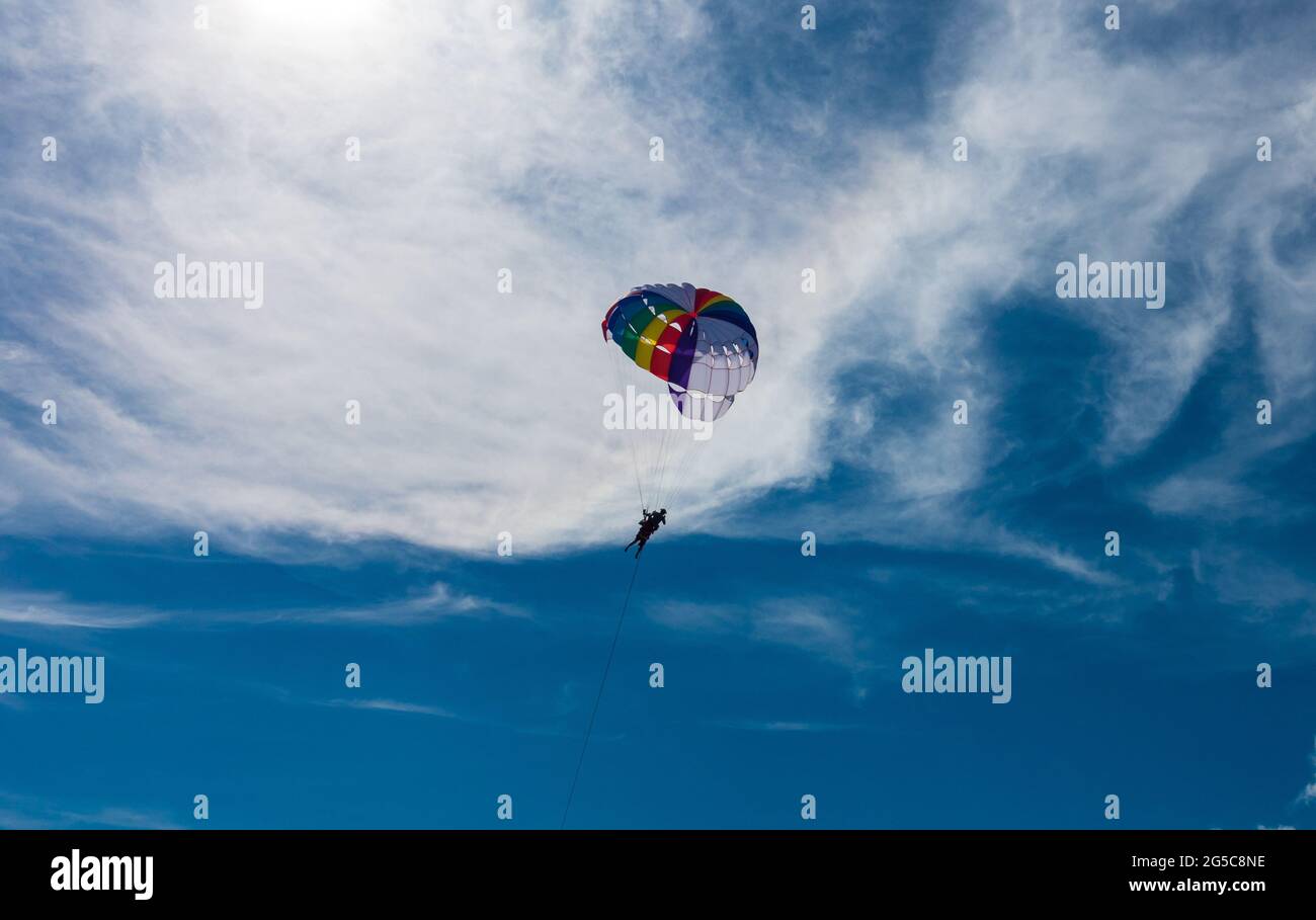 Parasailing, o parapendio o paracadutismo, un'attività di kiting ricreativo, che vola nel cielo blu chiaro. Attività in città di attrazione turistica. Foto Stock
