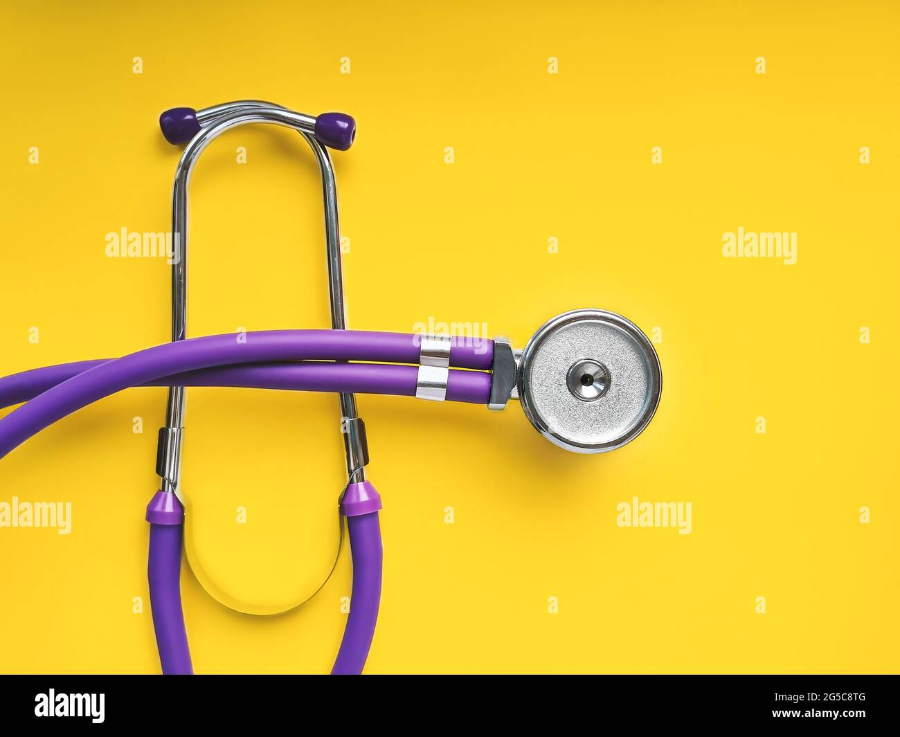 Stetoscopio medico lilla primo piano su sfondo giallo Foto Stock