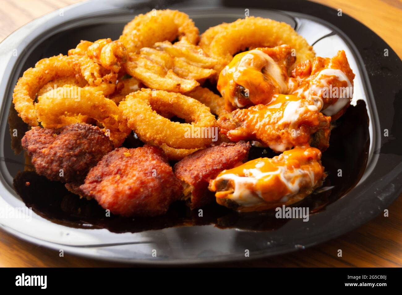 Fotografia di un piatto di ali di pollo con anelli di cipolla e patatine fritte Foto Stock