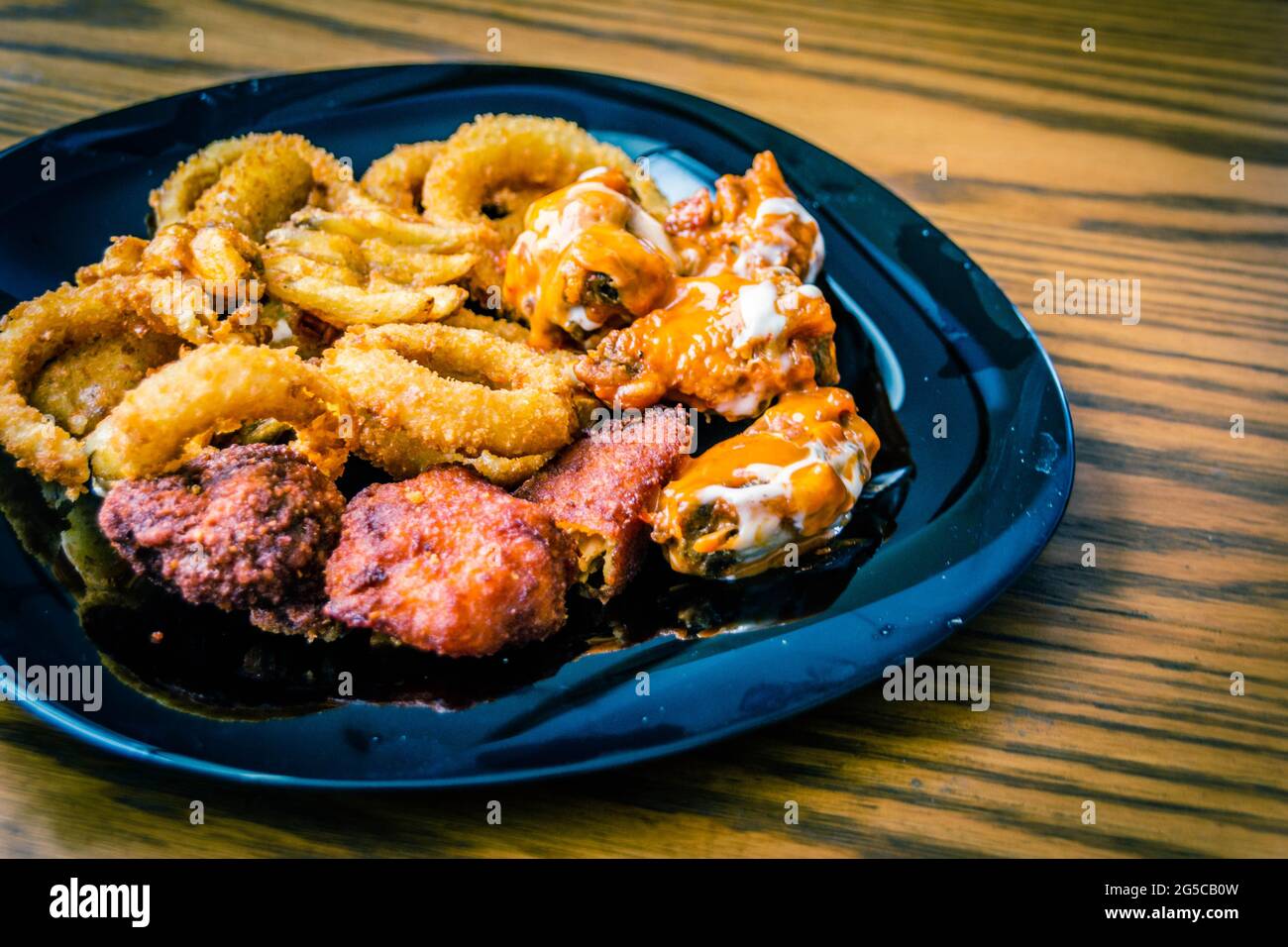 Fotografia di un piatto di ali di pollo con anelli di cipolla e patatine fritte Foto Stock