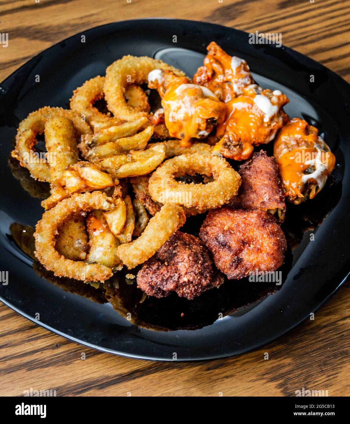 Fotografia di un piatto di ali di pollo con anelli di cipolla e patatine fritte Foto Stock