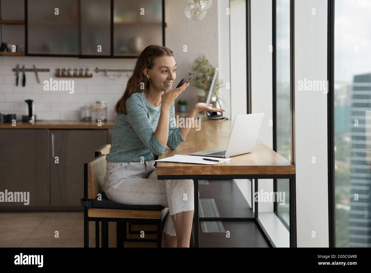 Felice giovane donna che registra un messaggio audio sul cellulare. Foto Stock