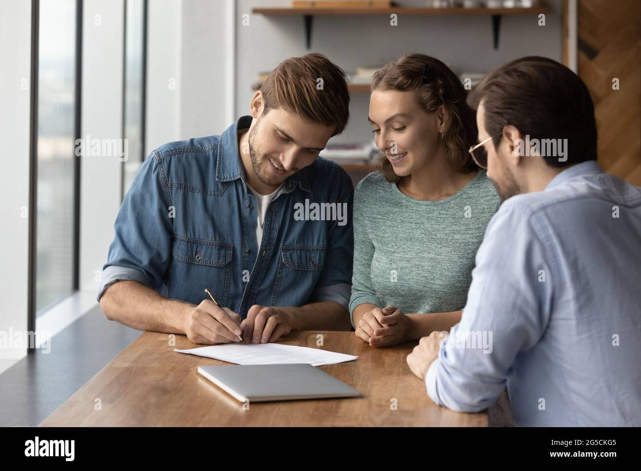 Felice giovane coppia cliente di famiglia firma del documento di assicurazione. Foto Stock