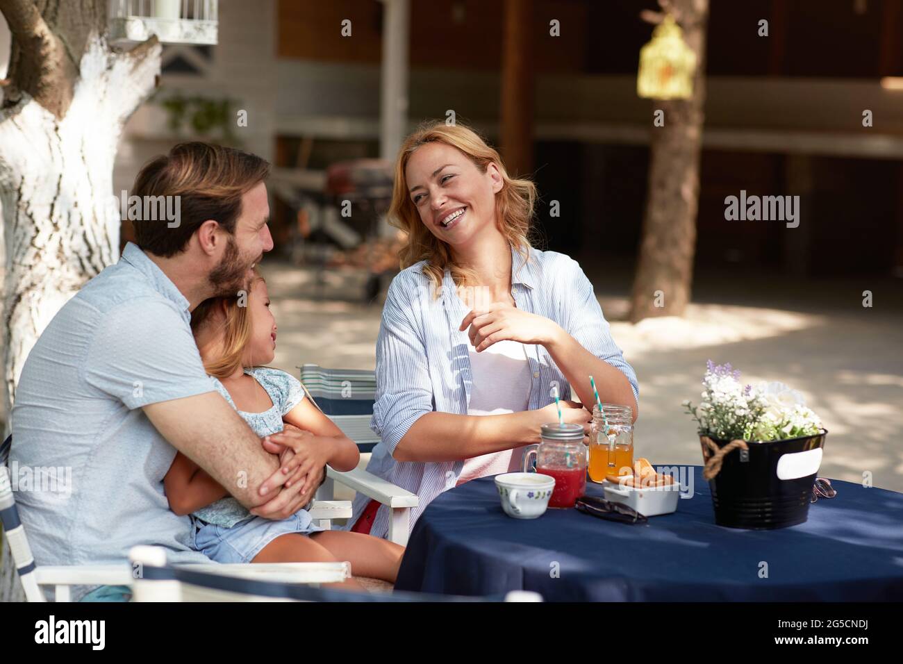 bella bionda caucasica ridendo e guardando il giovane papà arida con la figlia in braccio, seduto in grembo Foto Stock
