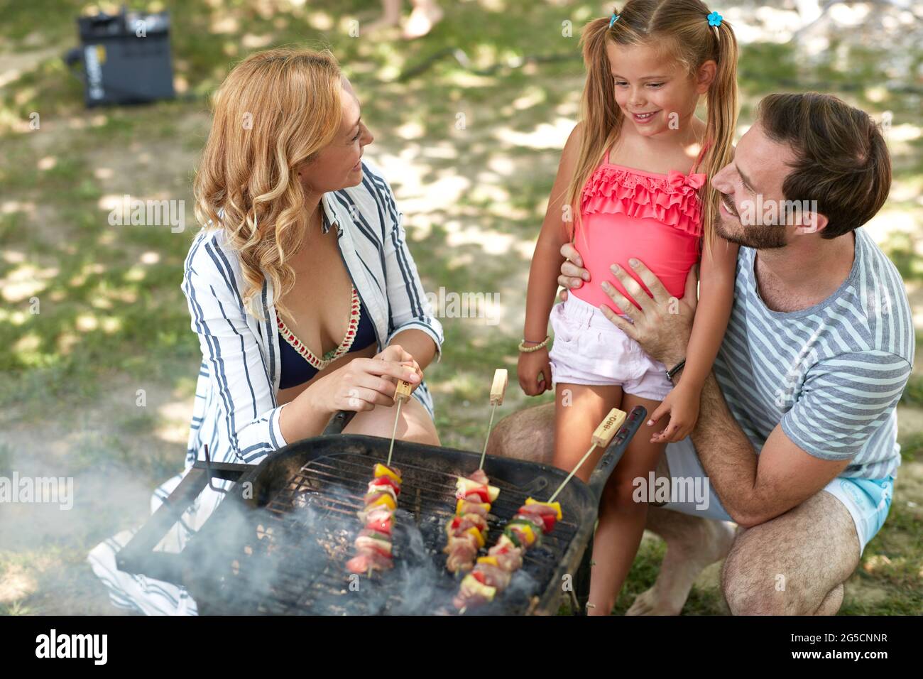 allegra famiglia caucasica di tre che fa barbecue all'aperto Foto Stock