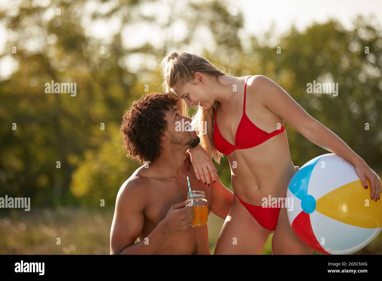 giovane coppia multietnica che si guarda da vicino nella natura, indossando costumi da bagno Foto Stock