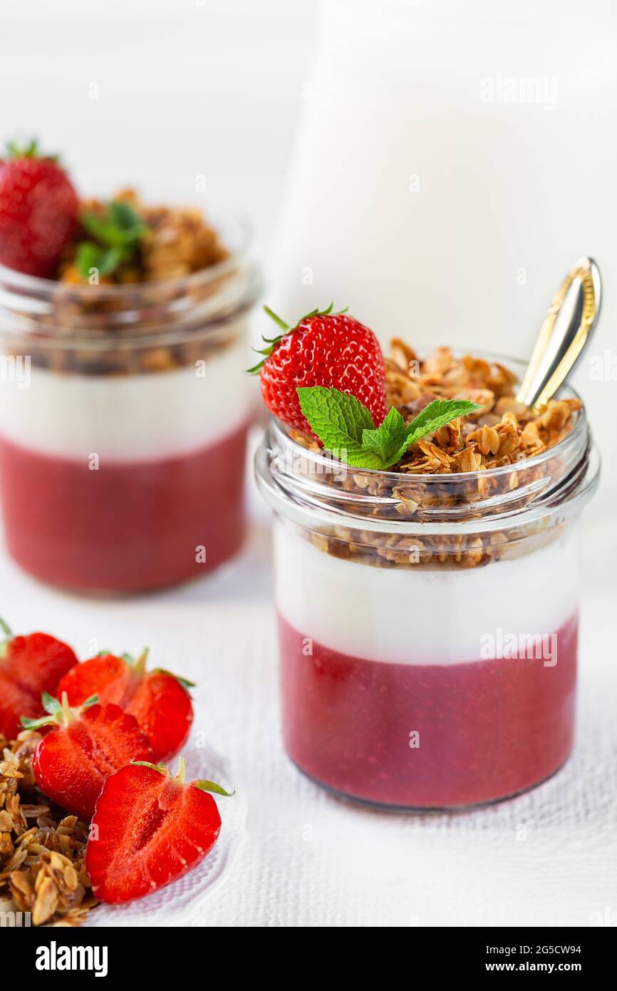 Yogurt con purea di fragole e granola in vasetti di vetro. Dessert. Foto Stock