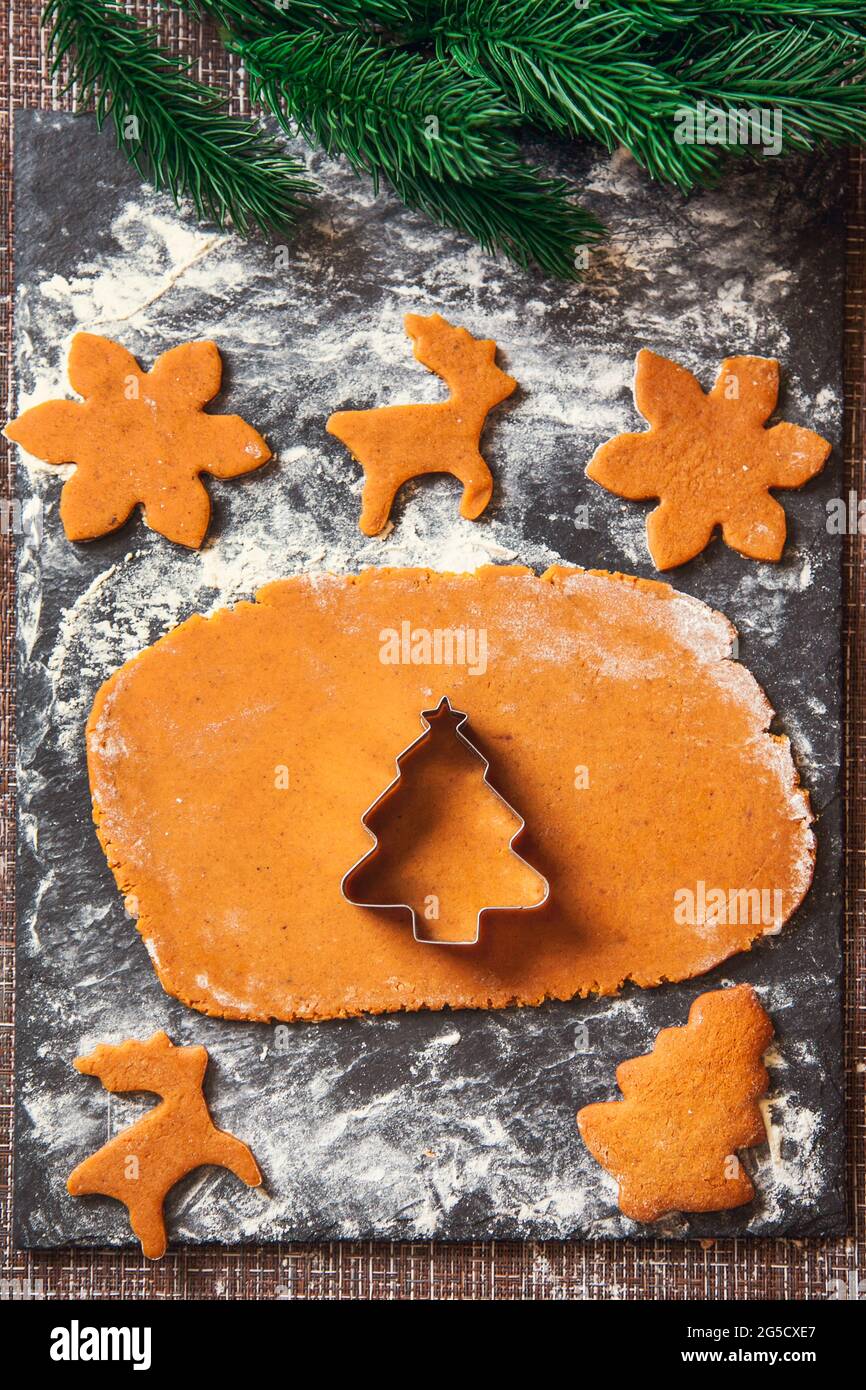 Il processo di fabbricazione dei biscotti dello zenzero di Natale. Una muffa a forma di albero di Natale su un impasto crudo per biscotti di pan di zenzero. Foto Stock