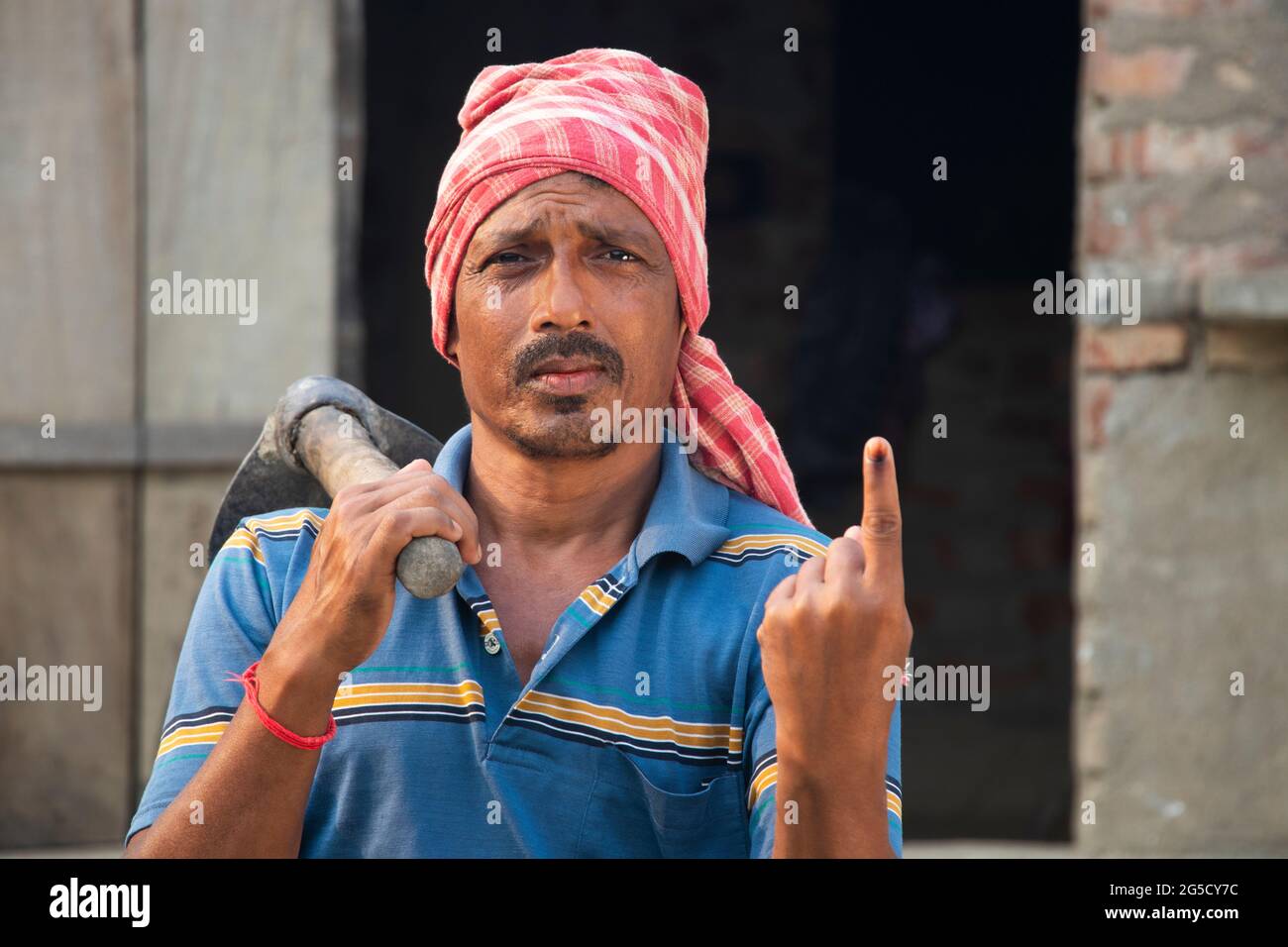 Ritratto di un agricoltore che tiene una pala con gli elettori segnati sul dito Foto Stock