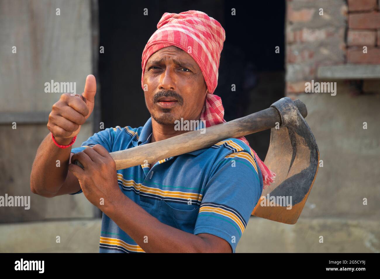 Ritratto di un agricoltore che tiene un escavatore mostrando pollici su segno Foto Stock