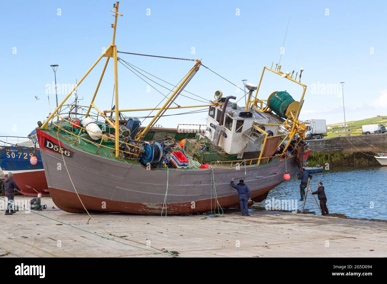 Pescatori che dipingano una barca da pesca, a Portmagee, Contea di Kerry, Irlanda Foto Stock