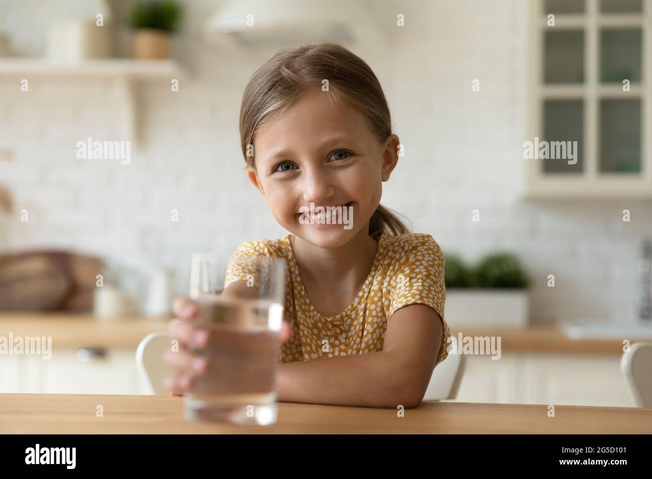 Sorridente bambina carina che propone aqua alla macchina fotografica. Foto Stock