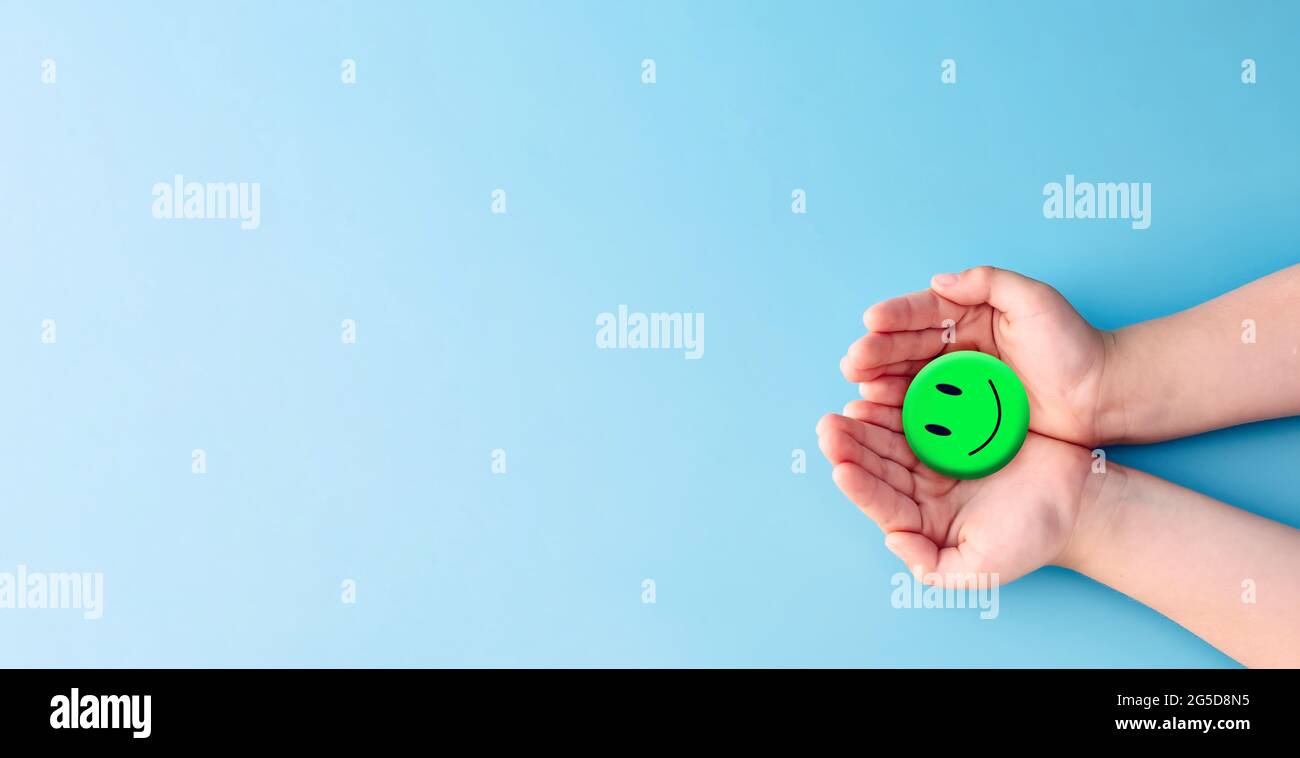 Concetto di giornata mentale mondiale di salute. Mano tenendo carta blu taglio sorriso felice faccia, pensiero positivo, valutazione della salute mentale . Foto Stock