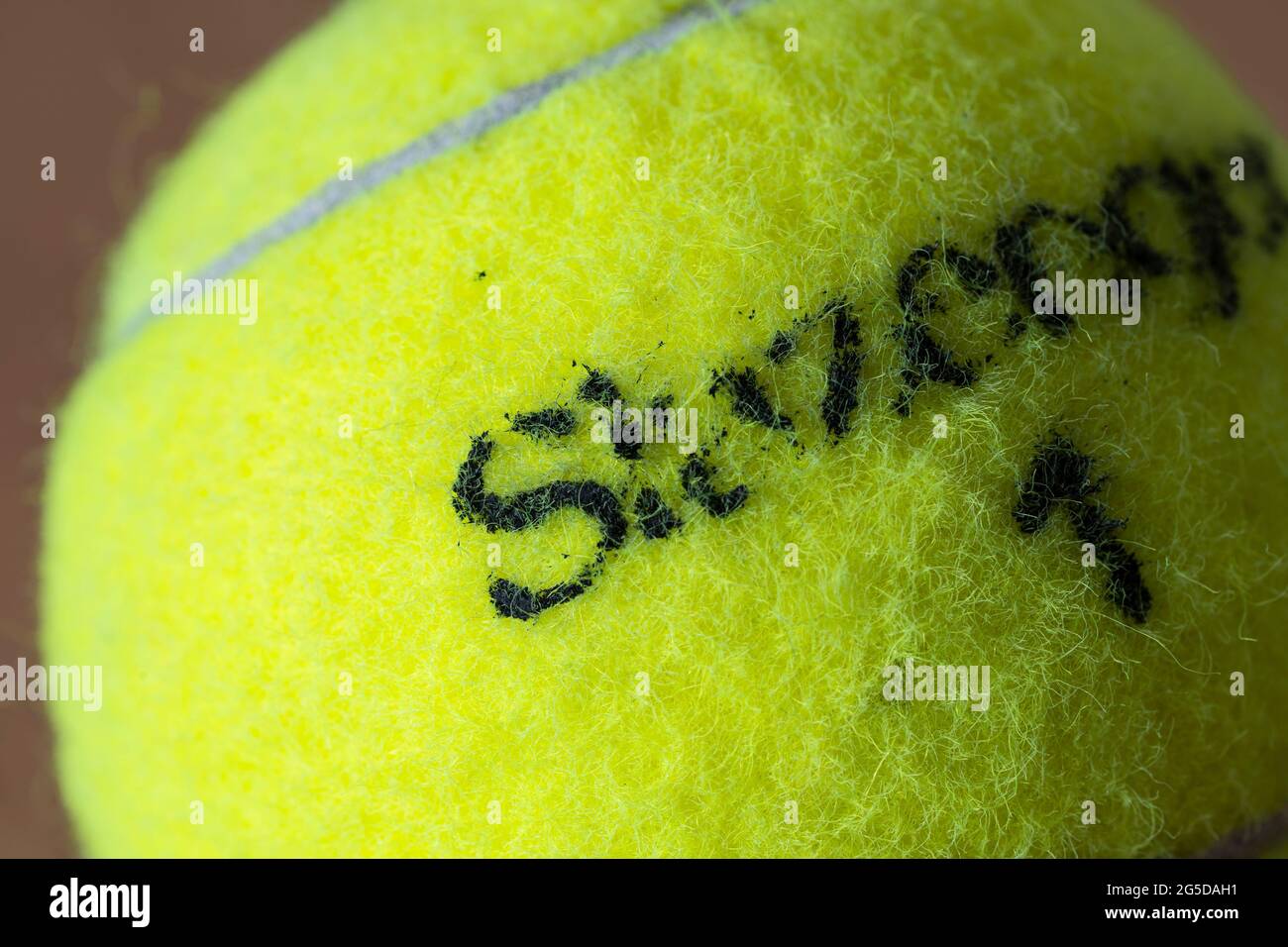 Macro closeup di una palla da tennis giallo fluorescente (giallo ottico) che mostra la copertura in feltro fibroso e il marchio Slazenger con il numero 1 Foto Stock