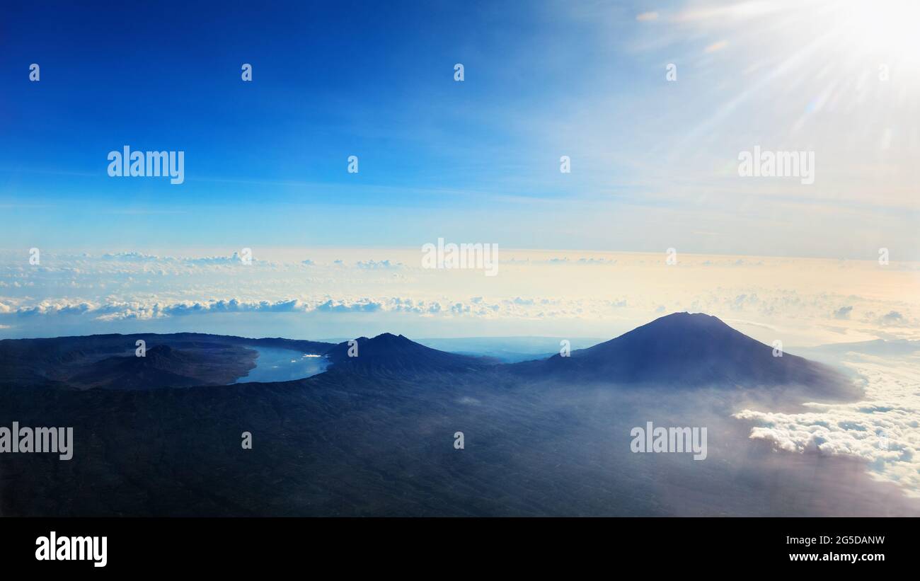Vista dalla finestra dell'aereo. Foto aerea di Agung - la vetta più alta dell'isola di Bali, il monte Abang, il vulcano attivo Batur con lago vulcanico in caldera. Foto Stock