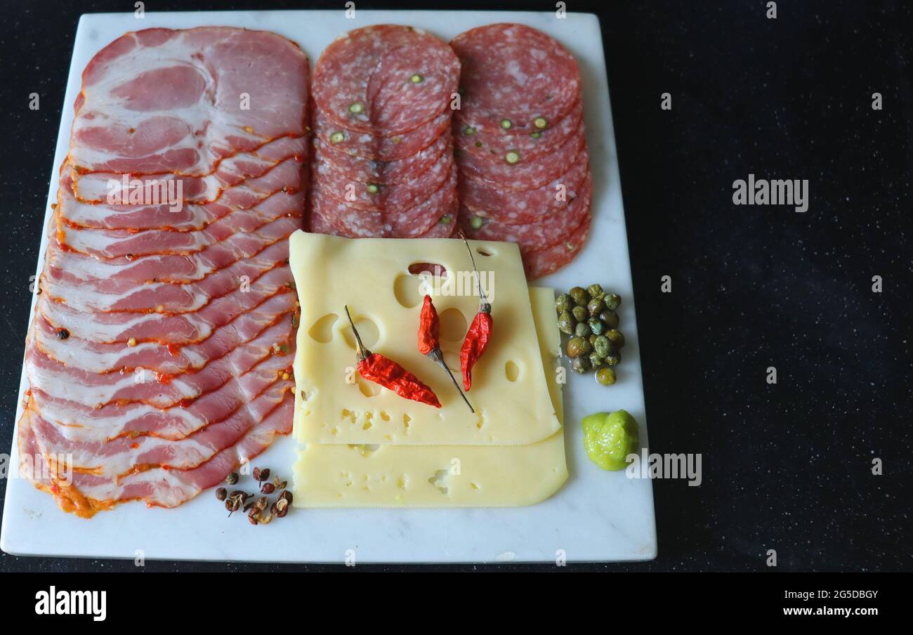 Ingredienti per il tavolo festivo, salame, formaggio, prosciutto e spezie, olive con pepe Foto Stock