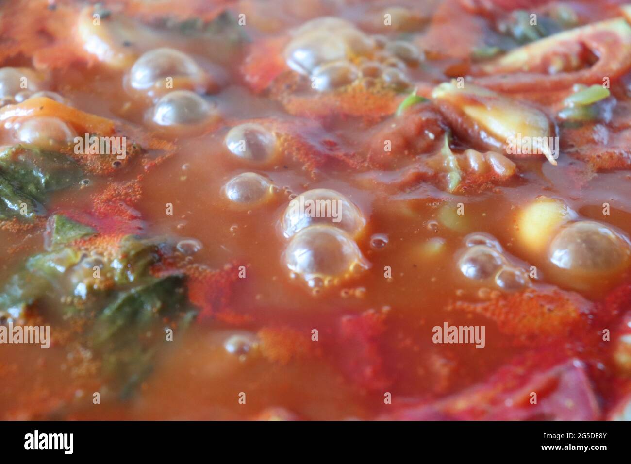 Stufato di verdure, ingredienti rossi e verdi in una padella sopra il fuoco Foto Stock