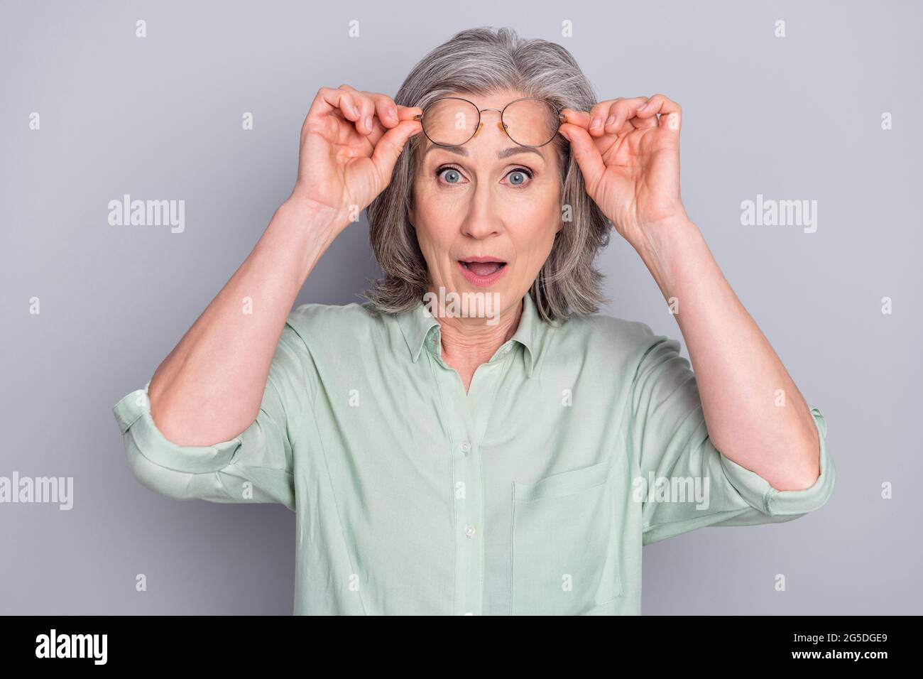 Ritratto di attraente stupito grigio-capelli donna notizie reazione WOW isolato su sfondo grigio colore pastello Foto Stock