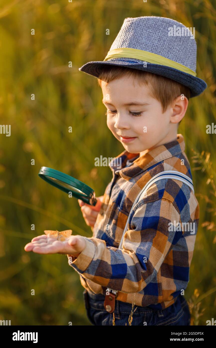 piccolo ragazzo che esplora la natura nel prato con una lente d'ingrandimento Foto Stock