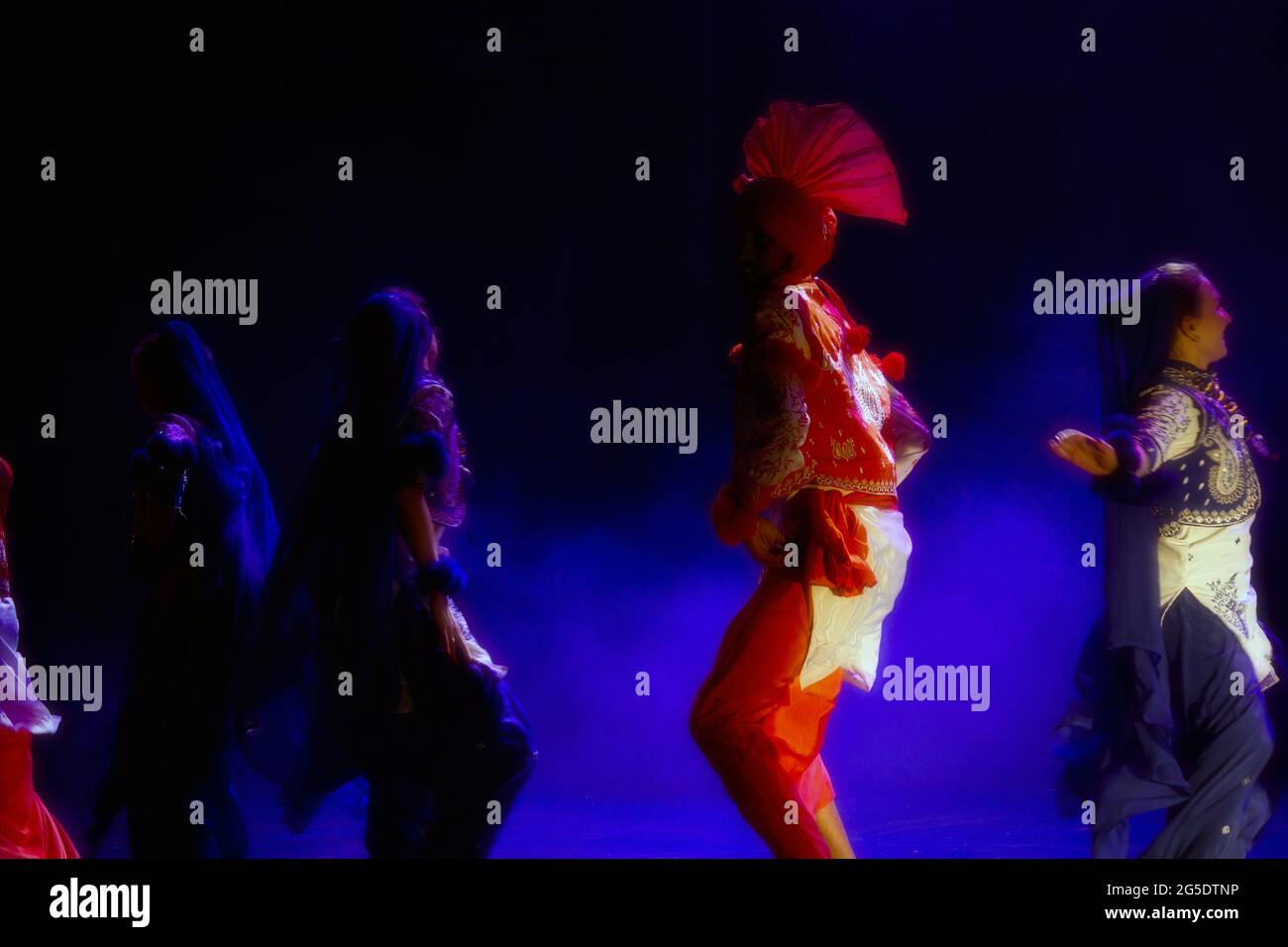 Cracovia, Polonia - 07 aprile 2018: Silhouette di mazzo di persone non identificate che eseguono la famosa danza Punjabi chiamato Bhangra in colorato dre tradizionale Foto Stock