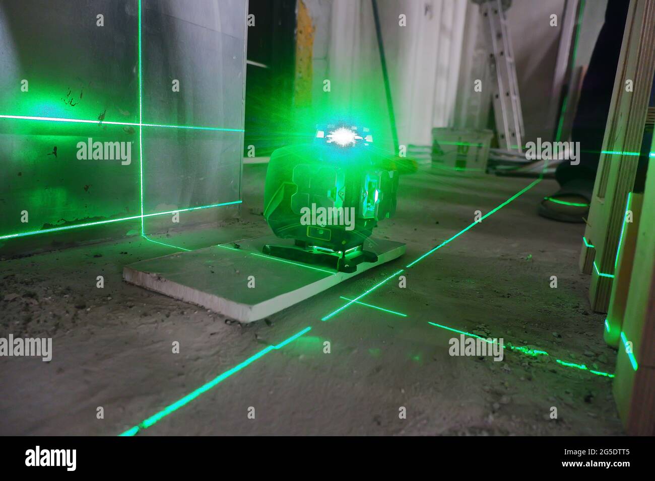 la livella laser si trova sul pavimento e traccia dei piani per l'installazione dei materiali da costruzione, Foto Stock