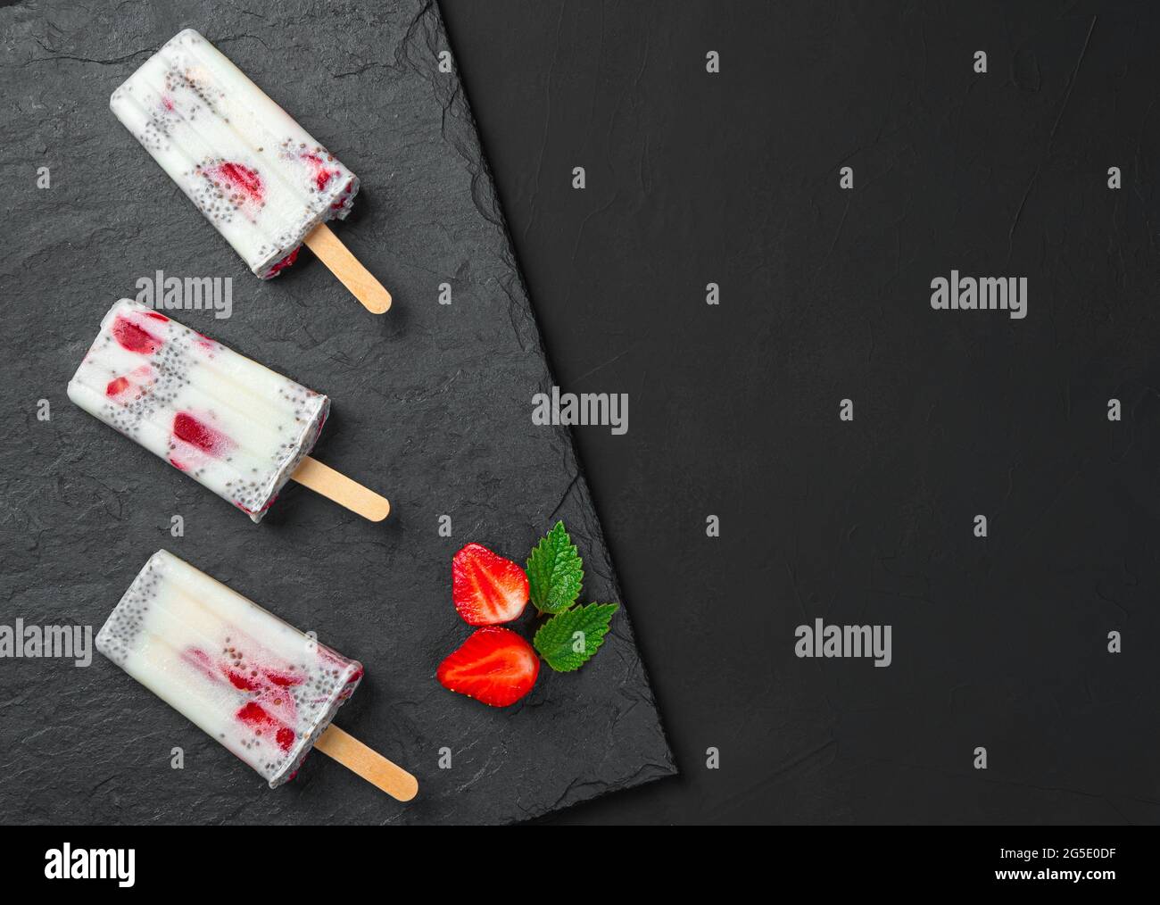 Tre gelati con fragole fresche e semi di cia su fondo nero. Dessert estivo sano. Foto Stock
