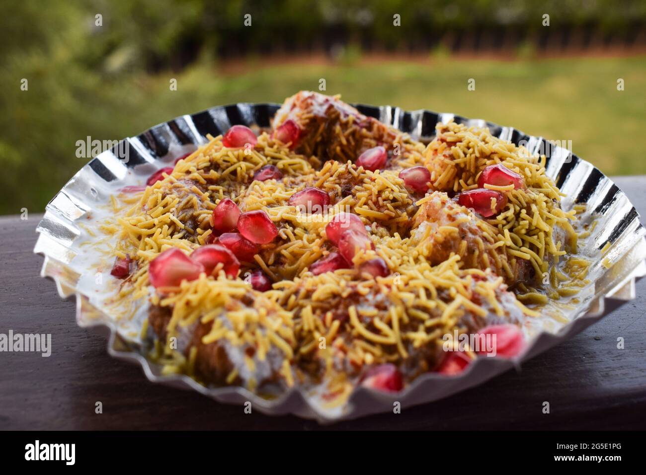 Dahi bhalla bhel chaat guarnito con SEV, semi di melograno, chaat masala con salse dolci e acose. Chaat indiano spuntini fatti in casa serviti in strada f Foto Stock