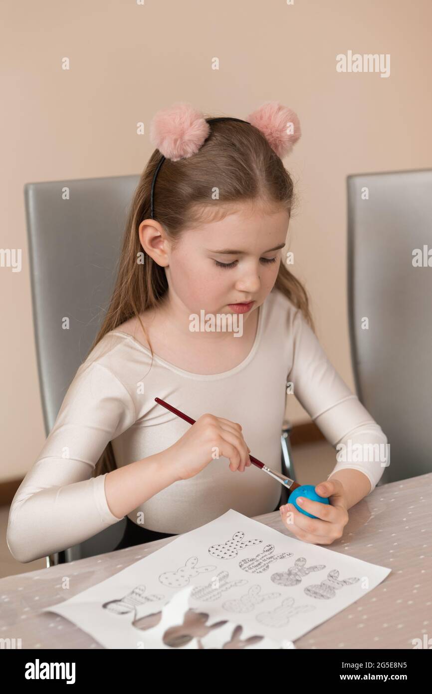 Una ragazza disegna un modello su un uovo colorato. Home preparativi per la vacanza di Pasqua Foto Stock