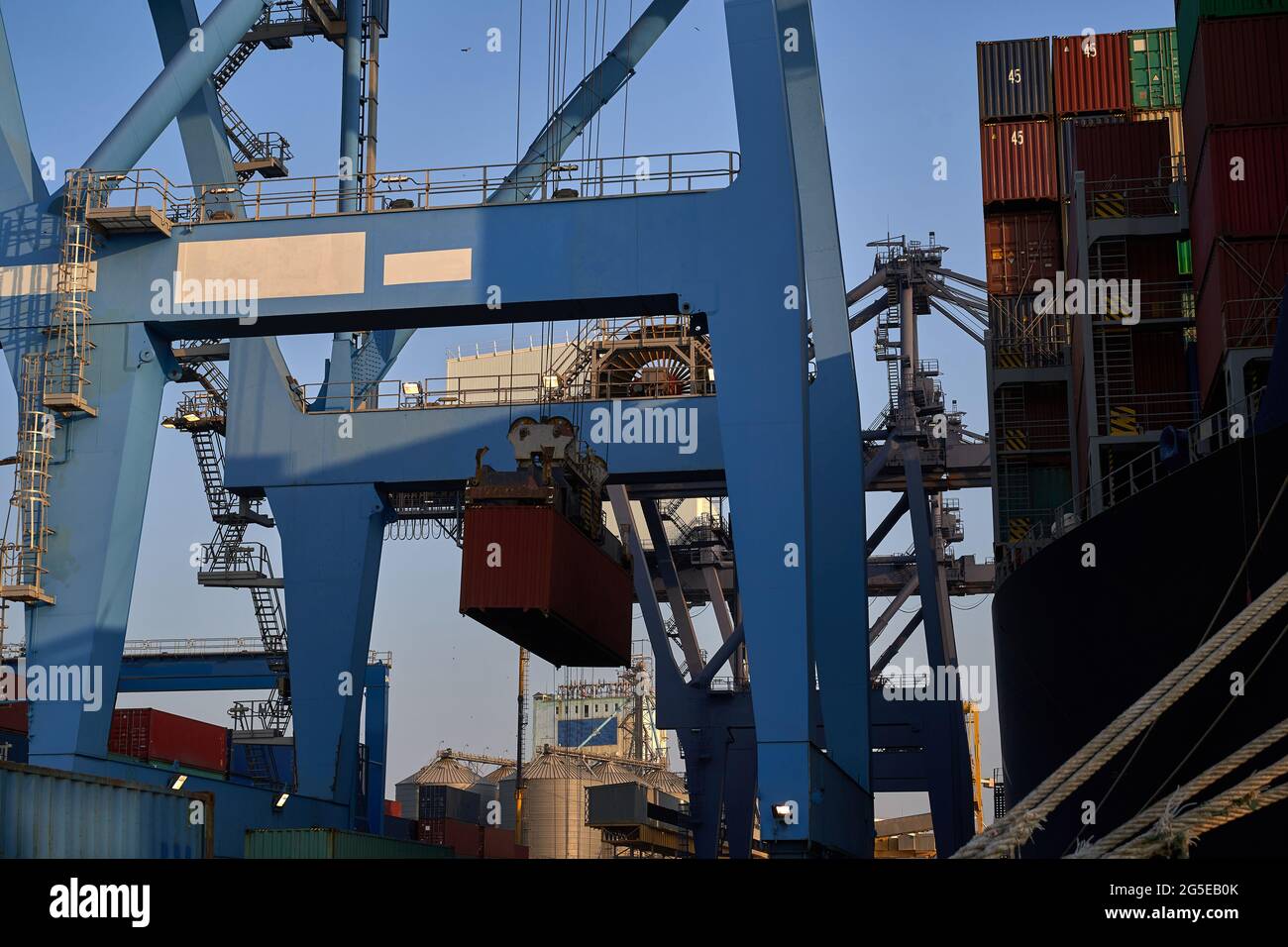 porta industriale con contenitori. La gru terminale carica il contenitore sulla nave Foto Stock