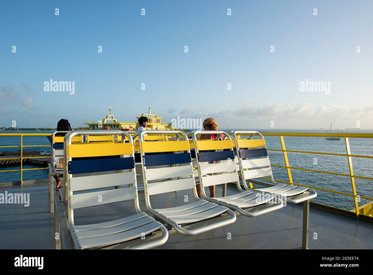 Ponte superiore di un traghetto RoRo e tre persone seduti guardando la vista del porto di Isla Mujeres, Messico Foto Stock