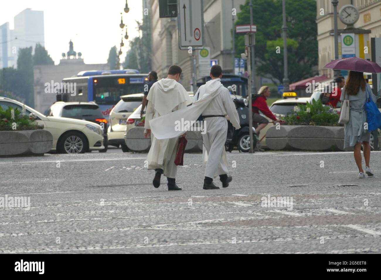 Due servitori d'altare hanno lasciato la chiesa e stanno attraversando l'Odeonsplatz Monaco, discutendo tra loro. Foto Stock