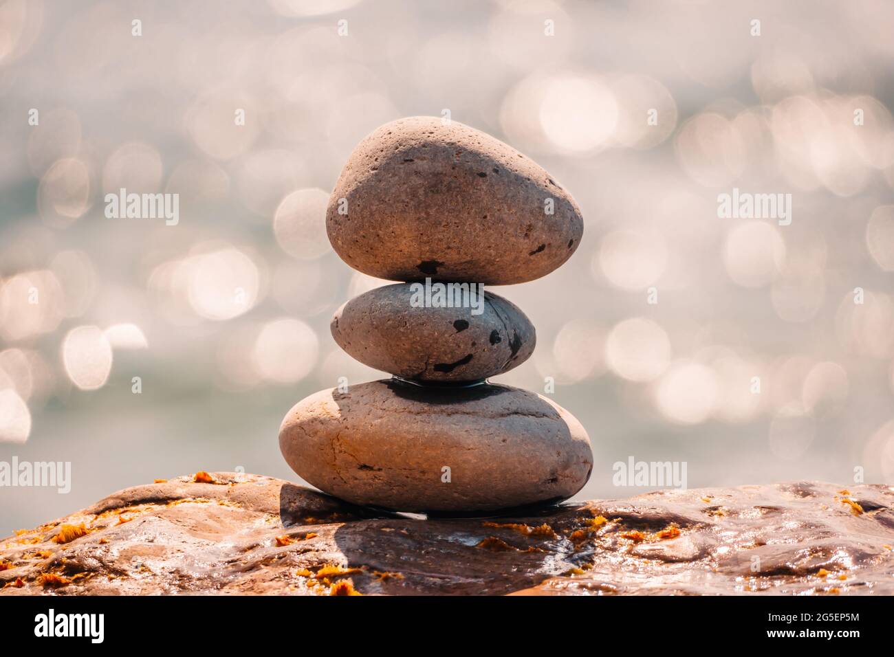 Equilibrata piramide di ciottoli sulla spiaggia in una giornata di sole. Abstract Sea bokeh sullo sfondo. Messa a fuoco selettiva. Pietre Zen sulla spiaggia di mare, meditazione Foto Stock