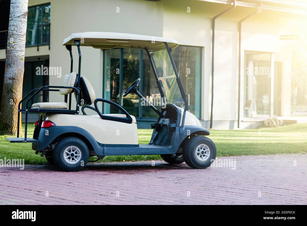 Attività ricreative all'aperto. Un golf cart bianco è parcheggiato vicino alla casa cottage moderna. Auto elettrica nel parcheggio dell'area del resort Foto Stock