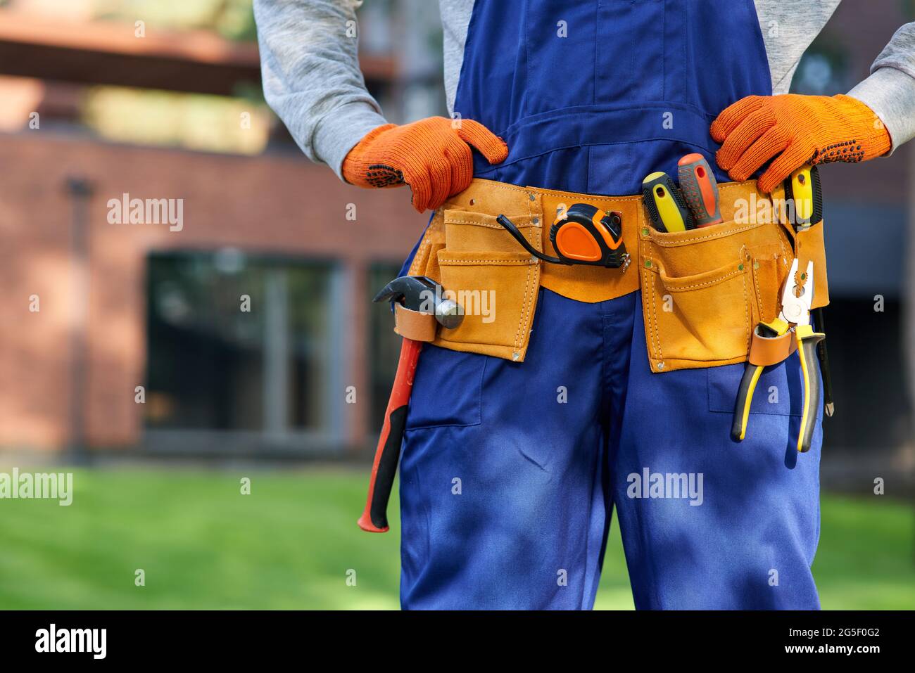Costruttore maschile in tute blu con cintura portautensili. Primo piano  sull'area della vita Foto stock - Alamy