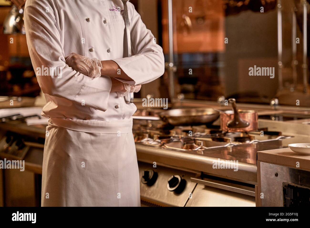 Braccia incrociate di chef ristorante accanto al fornello Foto Stock