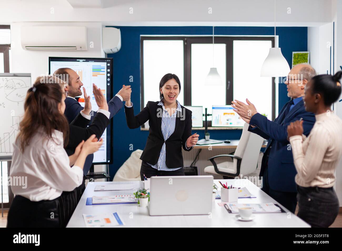 Felice diversi colleghi applaudendo dopo la presentazione di successo. I colleghi dei partner multietnici celebrano il successo del lavoro di squadra durante il briefing aziendale Foto Stock