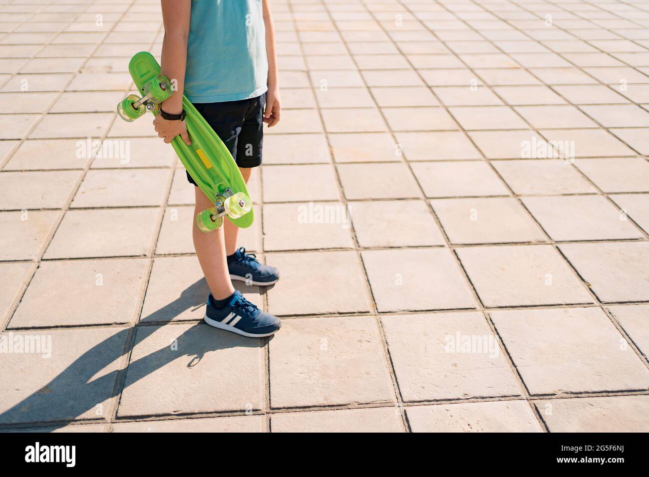 Giovane SCUOLA gambe COOL RAGAZZO che cammina con LA TAVOLA PENNY in le mani Foto Stock