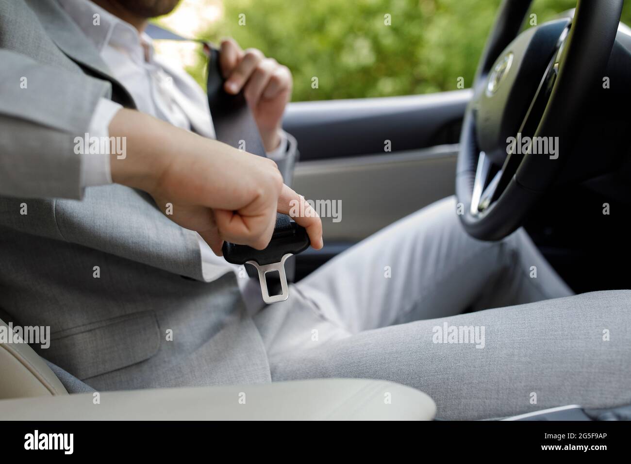 Vai al lavoro da solo. La mano maschile fissa la cintura di sicurezza  dell'auto mentre si è seduti all'interno dell'auto prima di guidare e di  procedere in sicurezza. Primo piano del pilota