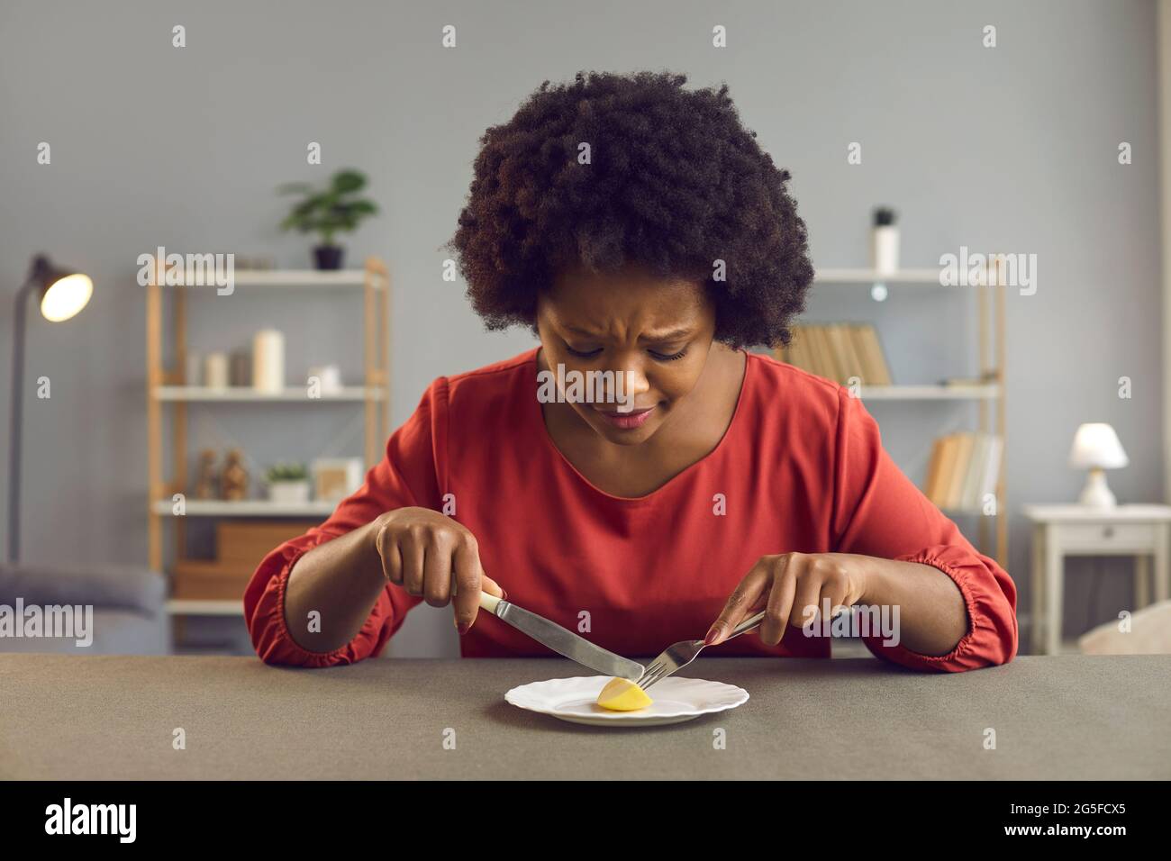 Triste giovane donna che sta attaccando alla dieta rigorosa che mangia un pezzo di mela per pranzo Foto Stock