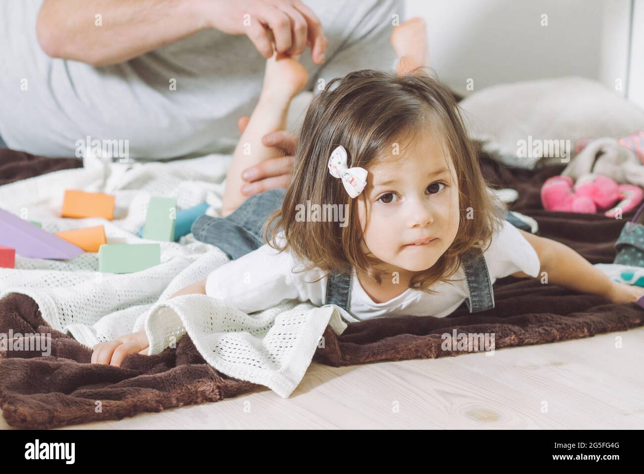 Padre gioca con la figlia piccola 2-4 sul pavimento. Papà solletico i piedi dei bambini. Famiglia, divertendosi Foto Stock