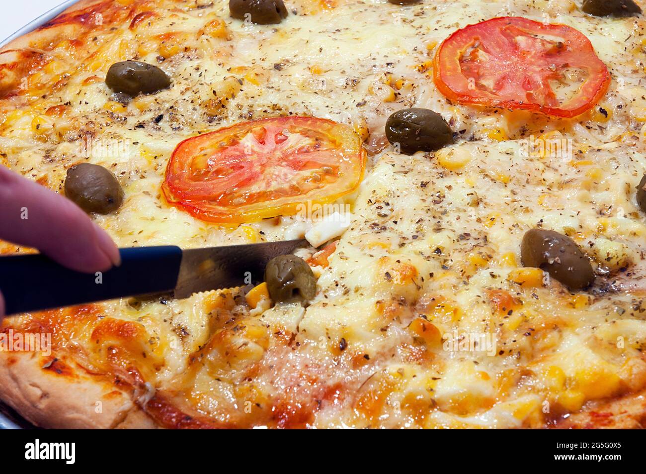 Pizza fatta a casa, gli ingredienti utilizzati erano olive, mozzarella, pomodori e mais. Foto Stock