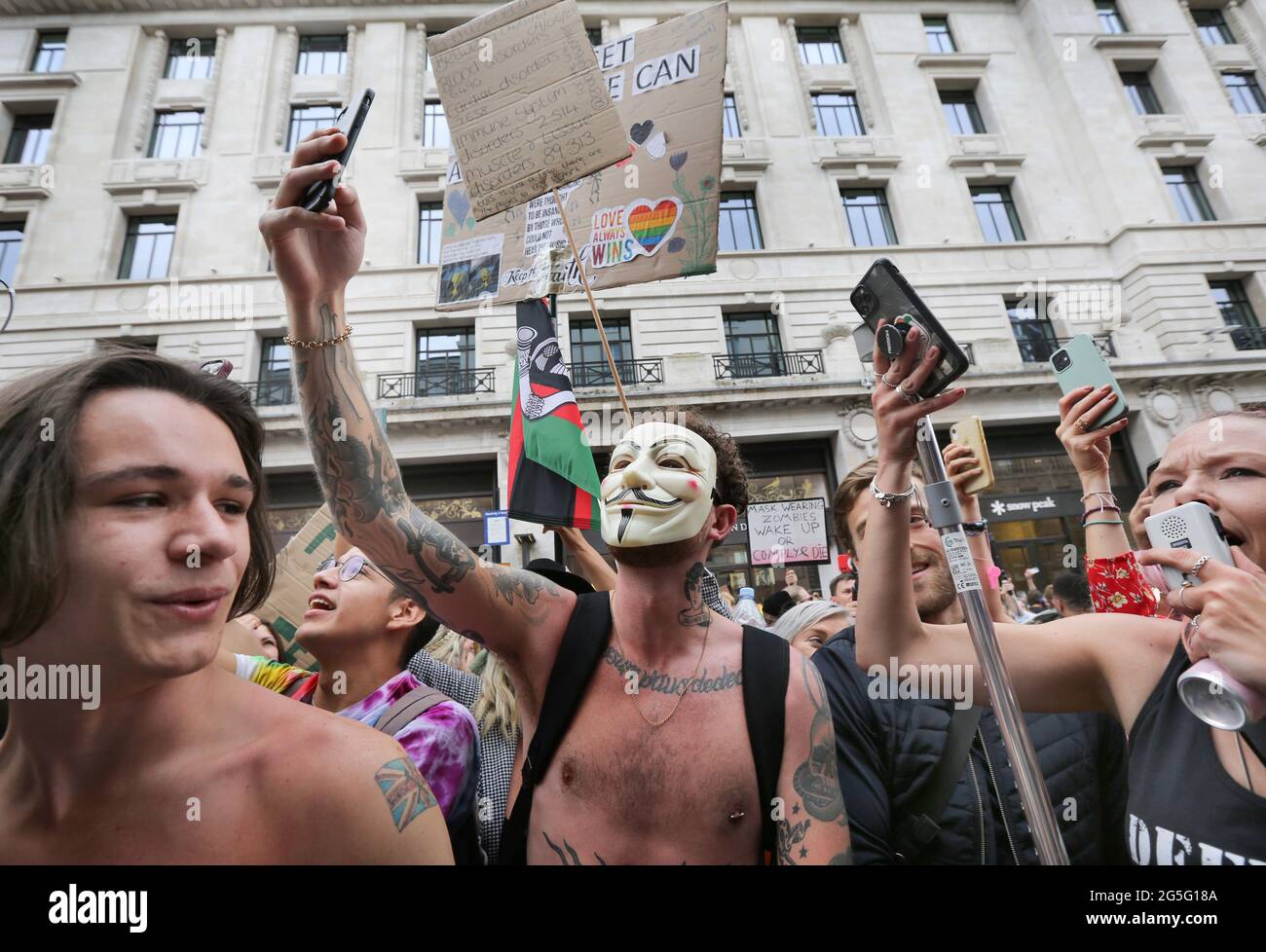 Un manifestante che indossa una maschera di fantasia ha visto scattare selfie mentre migliaia di manifestanti di libertà si portano a Regents Street durante la marcia della libertà chiedendo la fine delle restrizioni COVID-19, Londra. Foto Stock