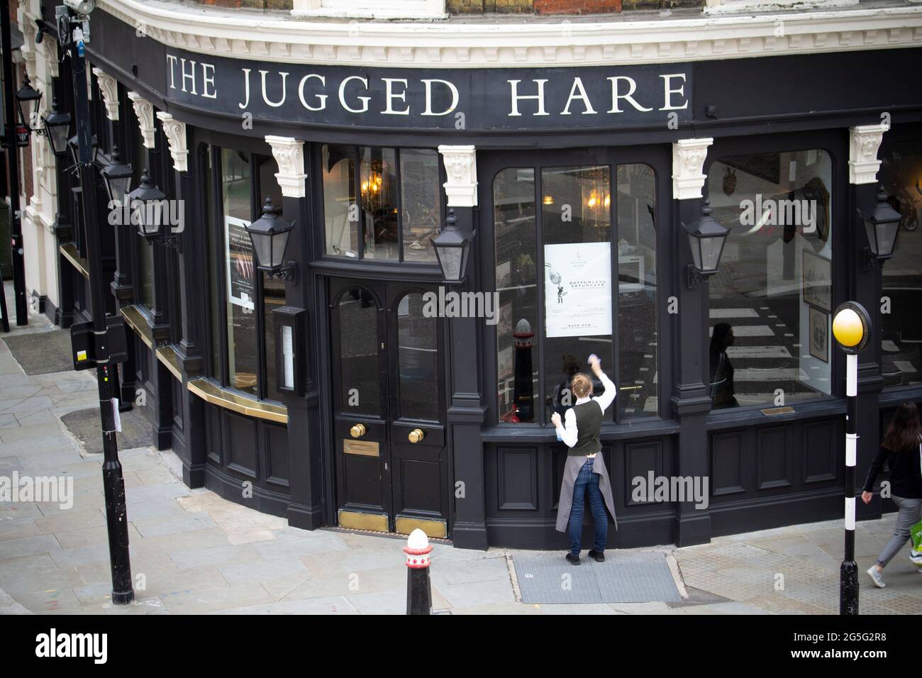 Il lavoratore del pub pulisce fuori della Jugged Hare Public House all'apertura, durante il coronavirus, covid-19, pandemia, nella città di Londra Foto Stock