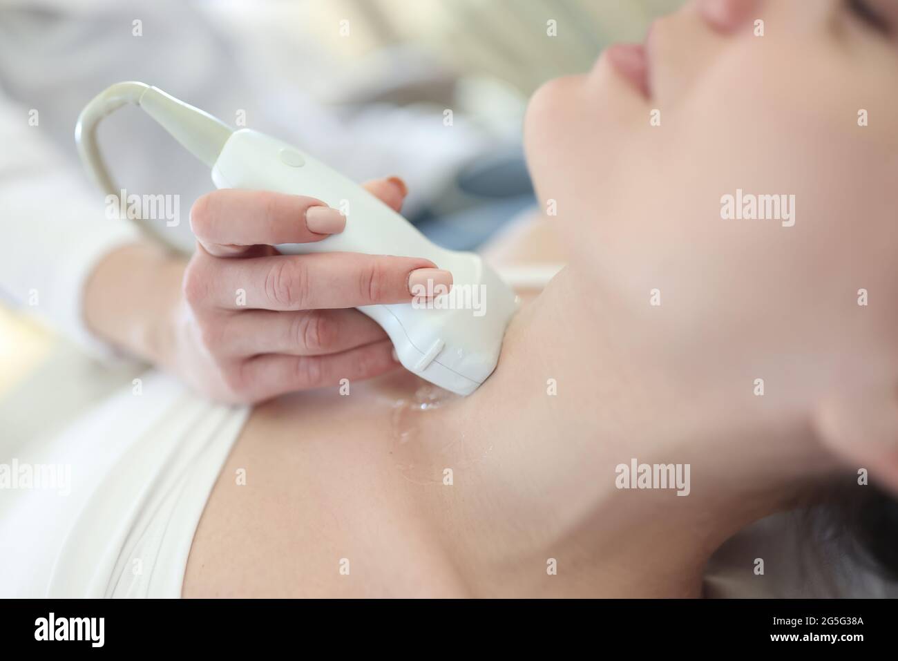 Medico che conduce ultrasuoni della ghiandola tiroidea a paziente di donna in closeup clinica Foto Stock