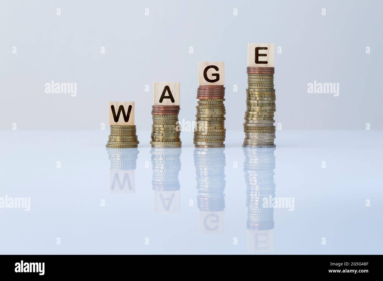 Parola 'SALARIO' su blocchi di legno in cima a pile ascendenti di monete. Foto concettuale di fare soldi, economia, affari, finanza, crescita finanziaria e successo. Foto Stock