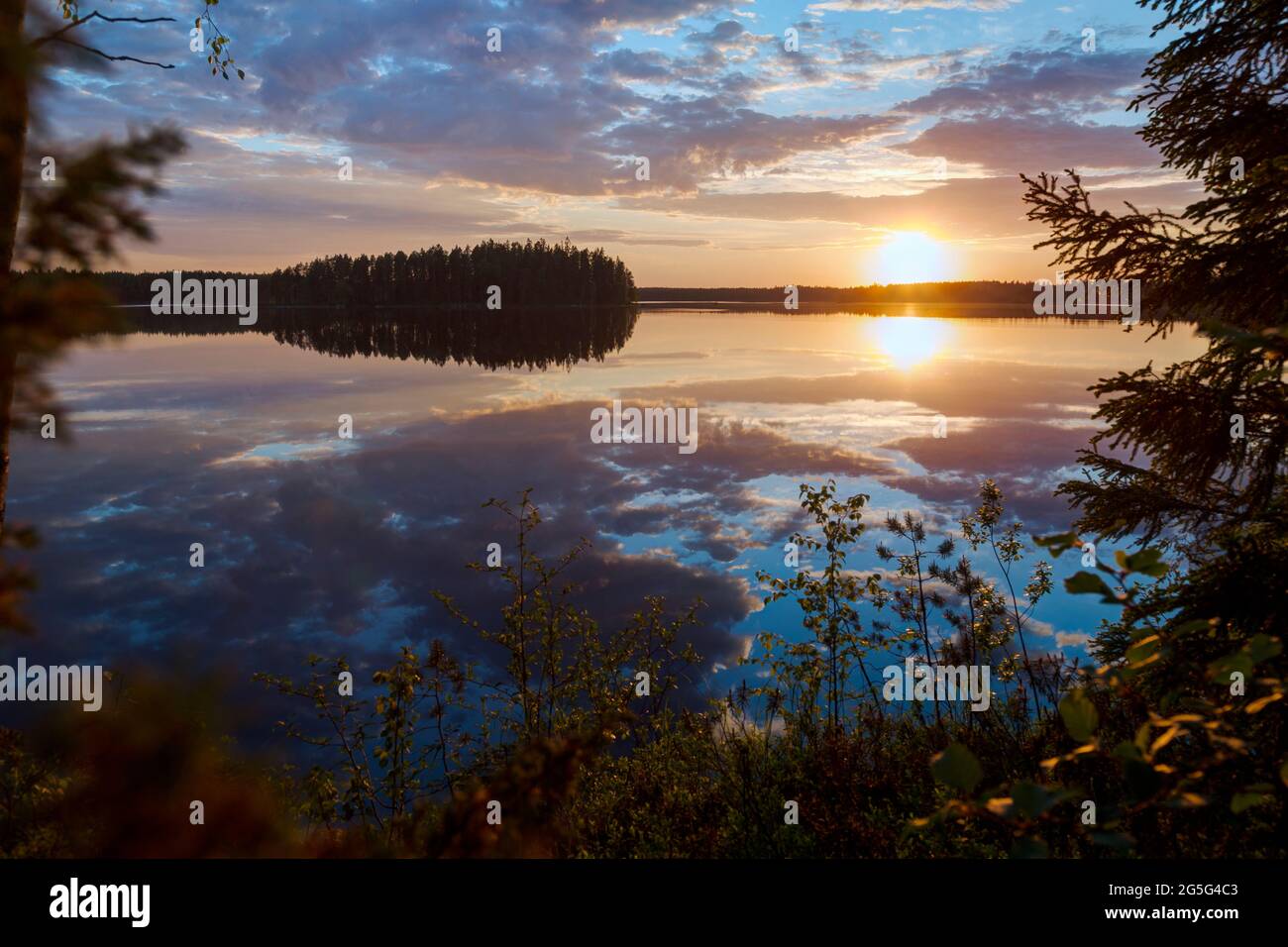 Scenico e bellissimo tramonto e suggestivo cielo nuvoloso e i loro riflessi su un lago calmo in Finlandia in estate. Foto Stock