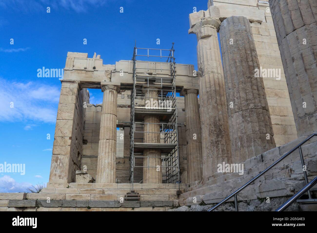 Colonne all'ingresso dell'Acropoli di Atene, Grecia, con ponteggi in metallo costruiti intorno ad una colonna in fase di riparazione con uno splendido sfondo blu del cielo Foto Stock