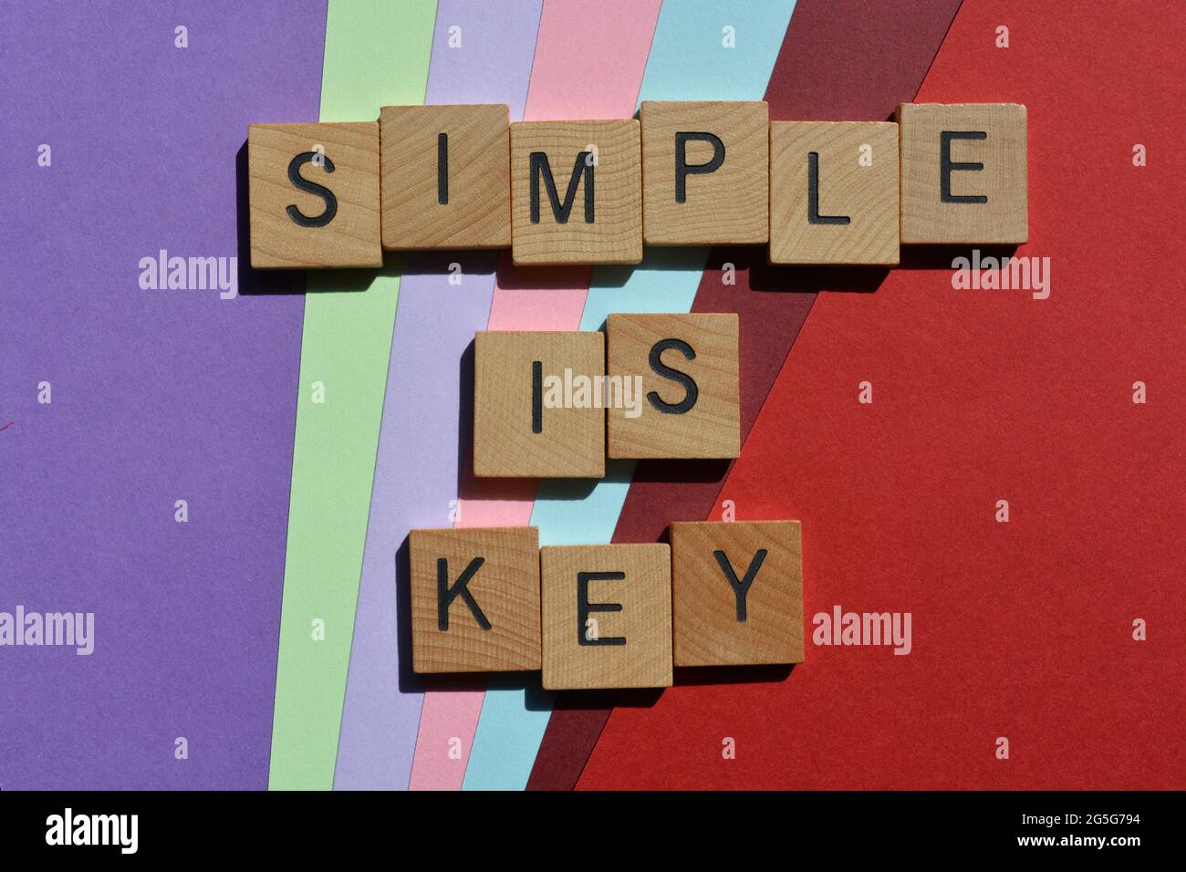 Semplice è chiave, parole in lettere alfabetiche in legno isolate su sfondo colorato Foto Stock